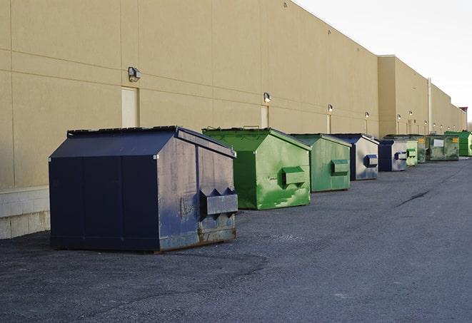 construction workers loading debris into dumpsters on a worksite in Delta, CO